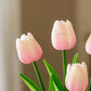 Baby pink tulips with green stems on a blurred brown background