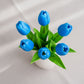 Blue tulips in a white vase on a white fabric background