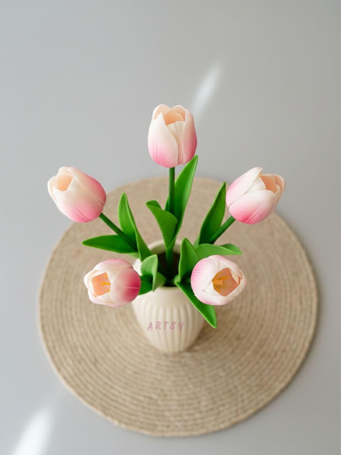 Decorative vase with pink tulips on a textured surface