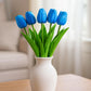 White vase with blue tulips on a wooden surface