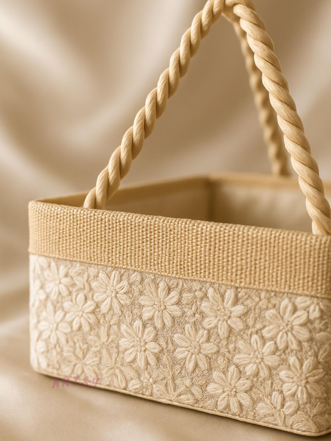 close up of cream decorative basket with floral embroidery and braided handle