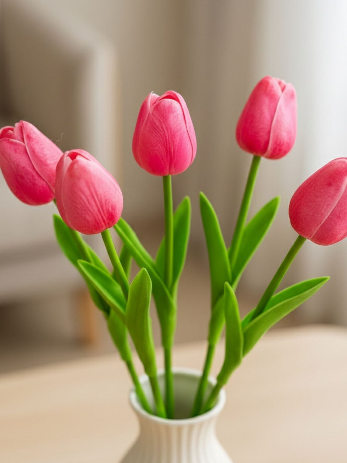 Pink tulips in a white vase on a blurred background