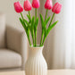 White vase with pink tulips on a wooden surface