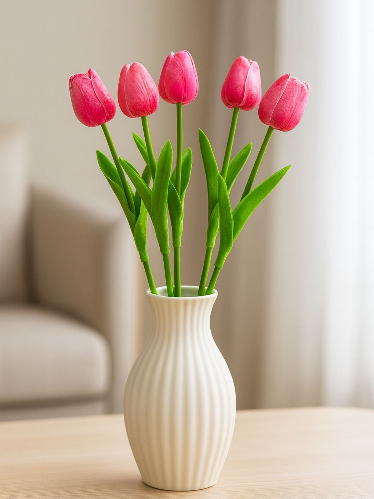 White vase with pink tulips on a wooden surface