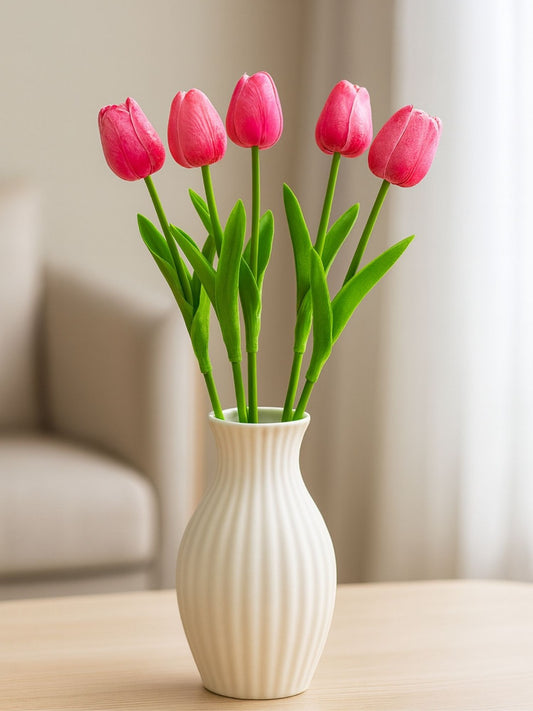 White vase with pink tulips on a wooden surface